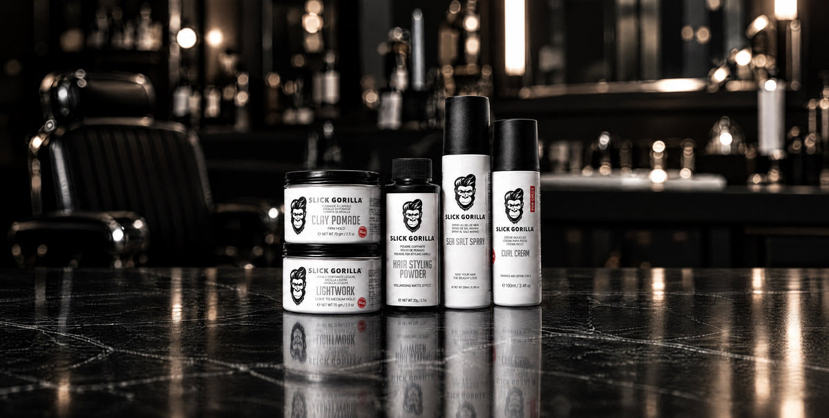 Slick Gorilla Clay Pomade, Lightwork, Hair Styling Powder, Sea Salt Spray and Curl Cream on a dark stone barbershop counter